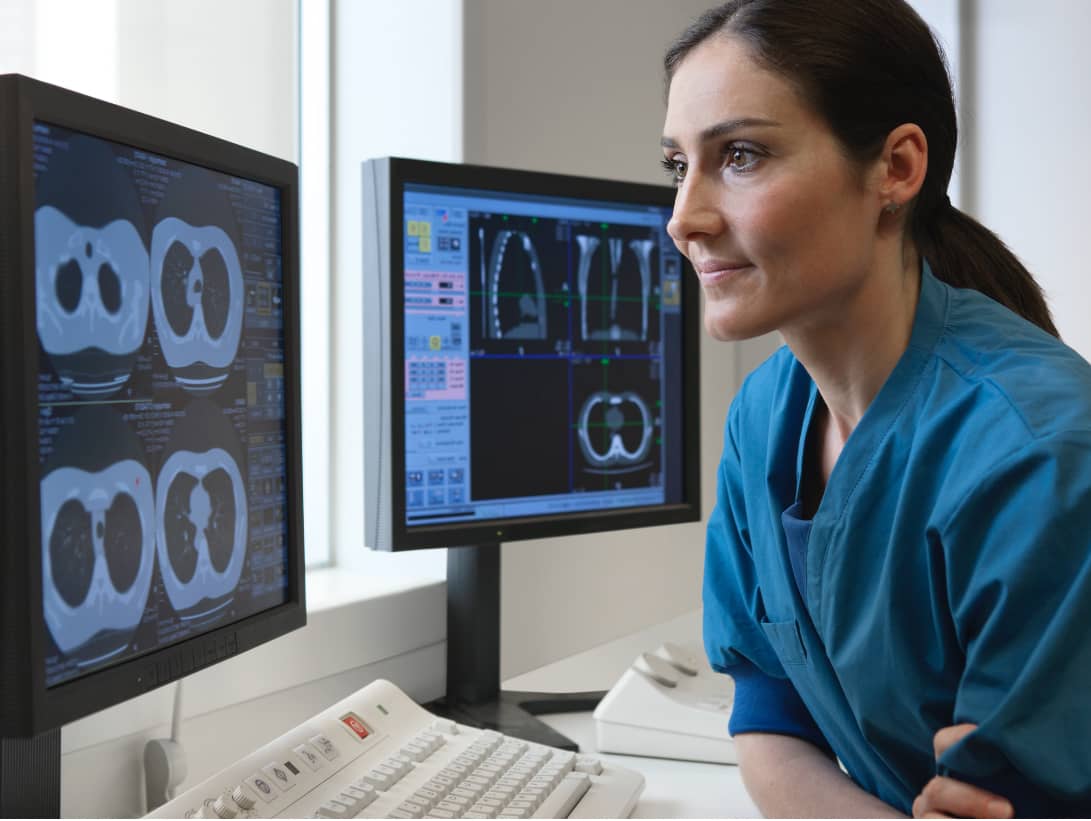 Woman radiologist viewing lung CT scans on video monitor