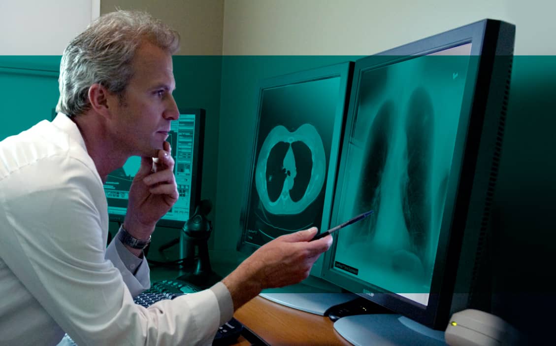Radiologist sits at desk and views lung Xrays
