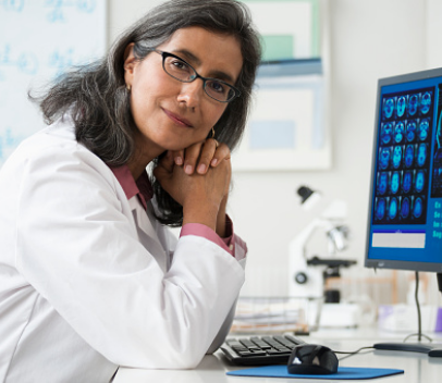 Radiologist smiles and poses to camera in front of CT scans
