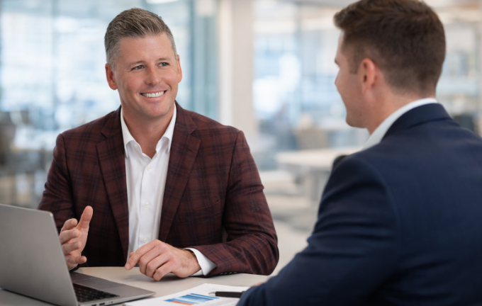 Two professionals engaged in a business discussion at a bright modern office, representing the marketing materials and sales collateral available from Riverain Technologies.