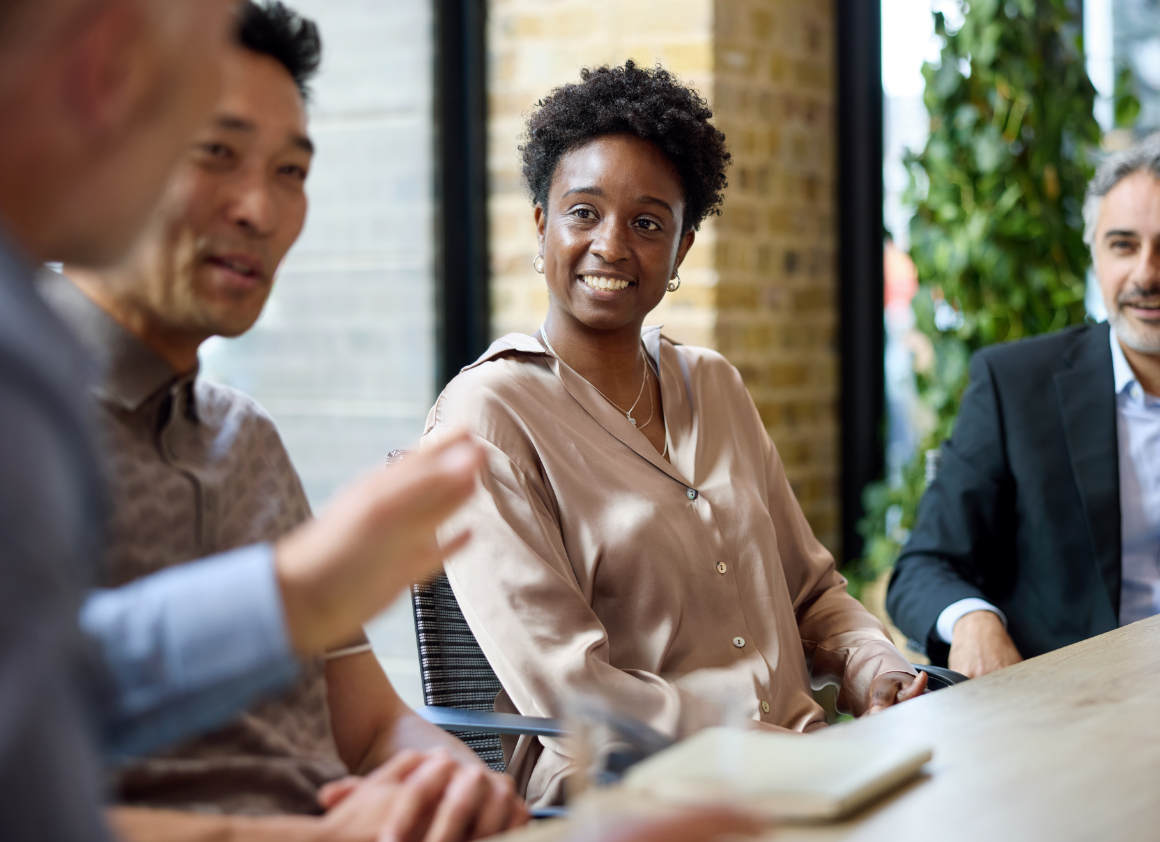Diverse team of professionals engaged in a collaborative meeting around a laptop, representing the partnership and integration relationships that power Riverain Technologies' AI radiology ecosystem.