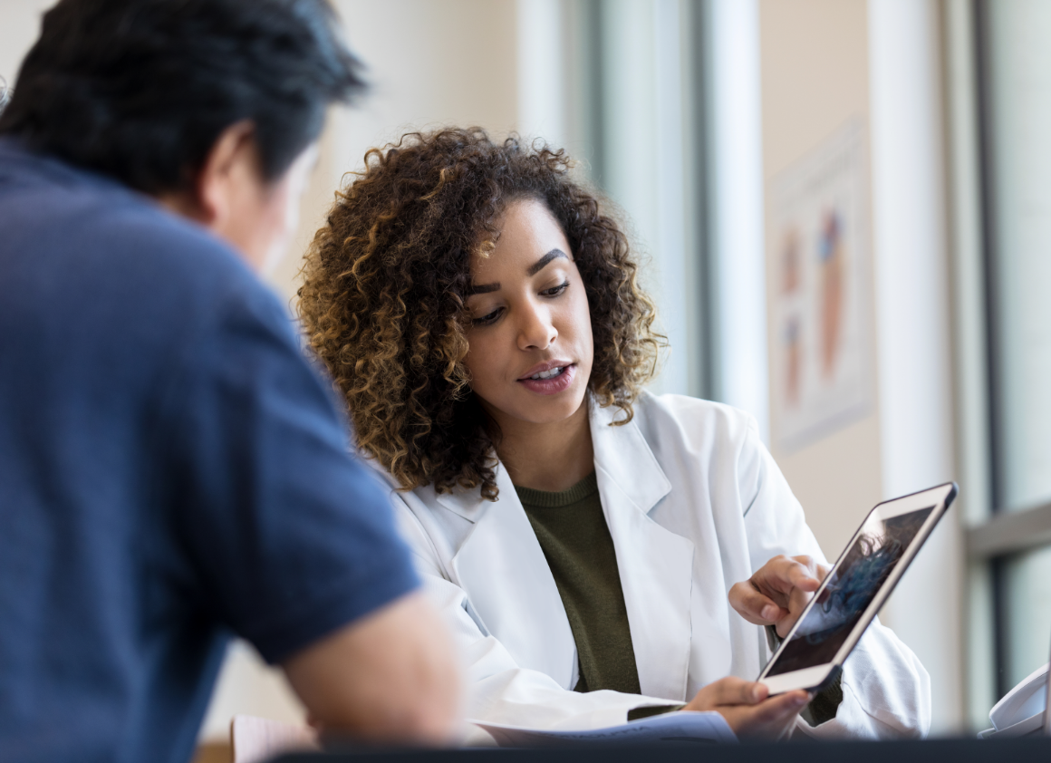 A healthcare provider shows clinical information on a tablet to a patient during a consultation, illustrating how Riverain Technologies empowers data-driven care decisions.